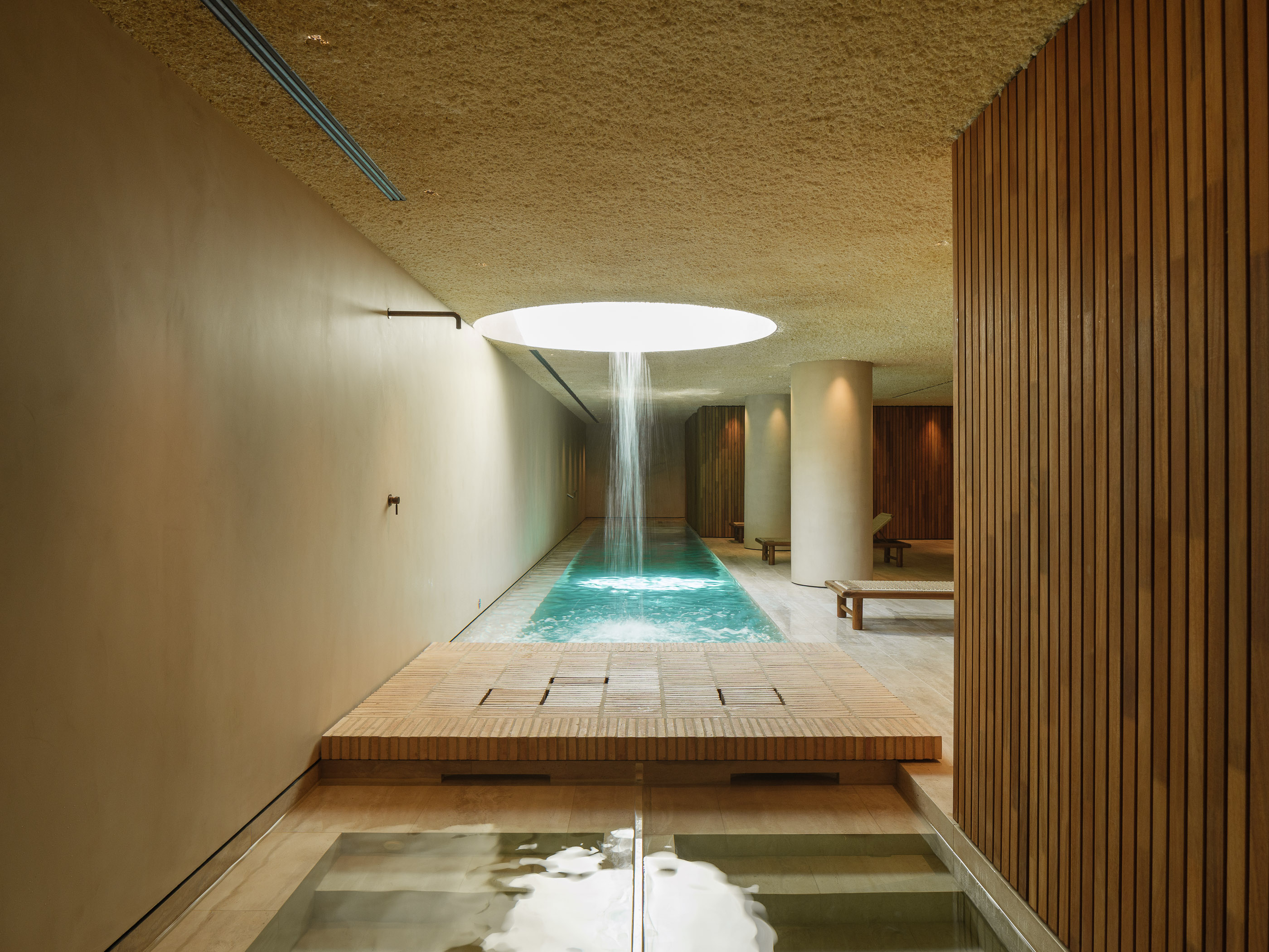Interior d'un SPA d'hotel reformat al Maresme per a [Nom del teu Despatx]. Disseny arquitectònic minimalista amb llum zenital, tons càlids i materials naturals per a la zona d'aigües.